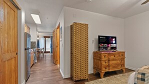 Ein Flur mit Holzschränken, einem Kühlschrank und einem Fernseher auf einer Holzkommode.