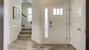 Ein Korridor mit Holzboden, weißen Türen und einer Treppe, die zu einem anderen Raum führt.