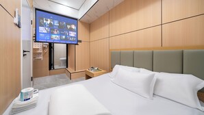 A hotel room with a bed, a TV mounted on the wall, a wooden wardrobe, and a small bedside table. - Windsor Hella Inn (Kowloon)