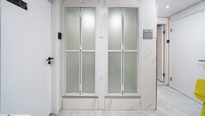 A hallway with a double door, a sign indicating room number 03, and a yellow chair in the corner. - Windsor Hella Inn (Kowloon)