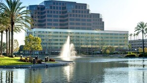 A modern hotel with a central courtyard, a fountain, and a body of water reflecting the building. - Orange County Hotel (Santa Ana)