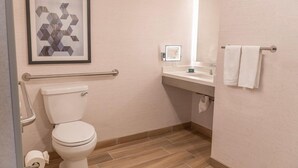 A bathroom with a toilet, a sink, a mirror, a towel rack, and a framed artwork on the wall. - Orange County Hotel (Santa Ana)