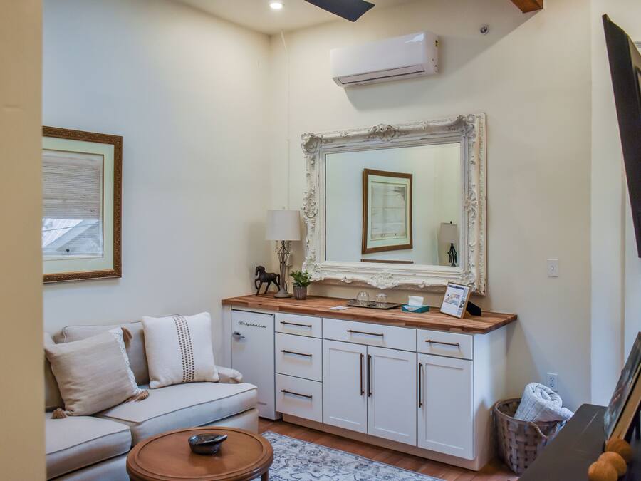 A living room with a sofa, a coffee table, a cabinet, and a large mirror.