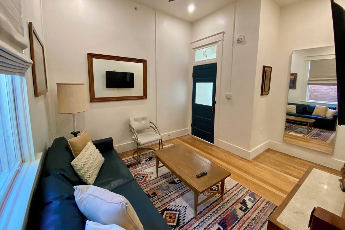 A modern living room with a blue sofa, a wooden coffee table, and a patterned rug.