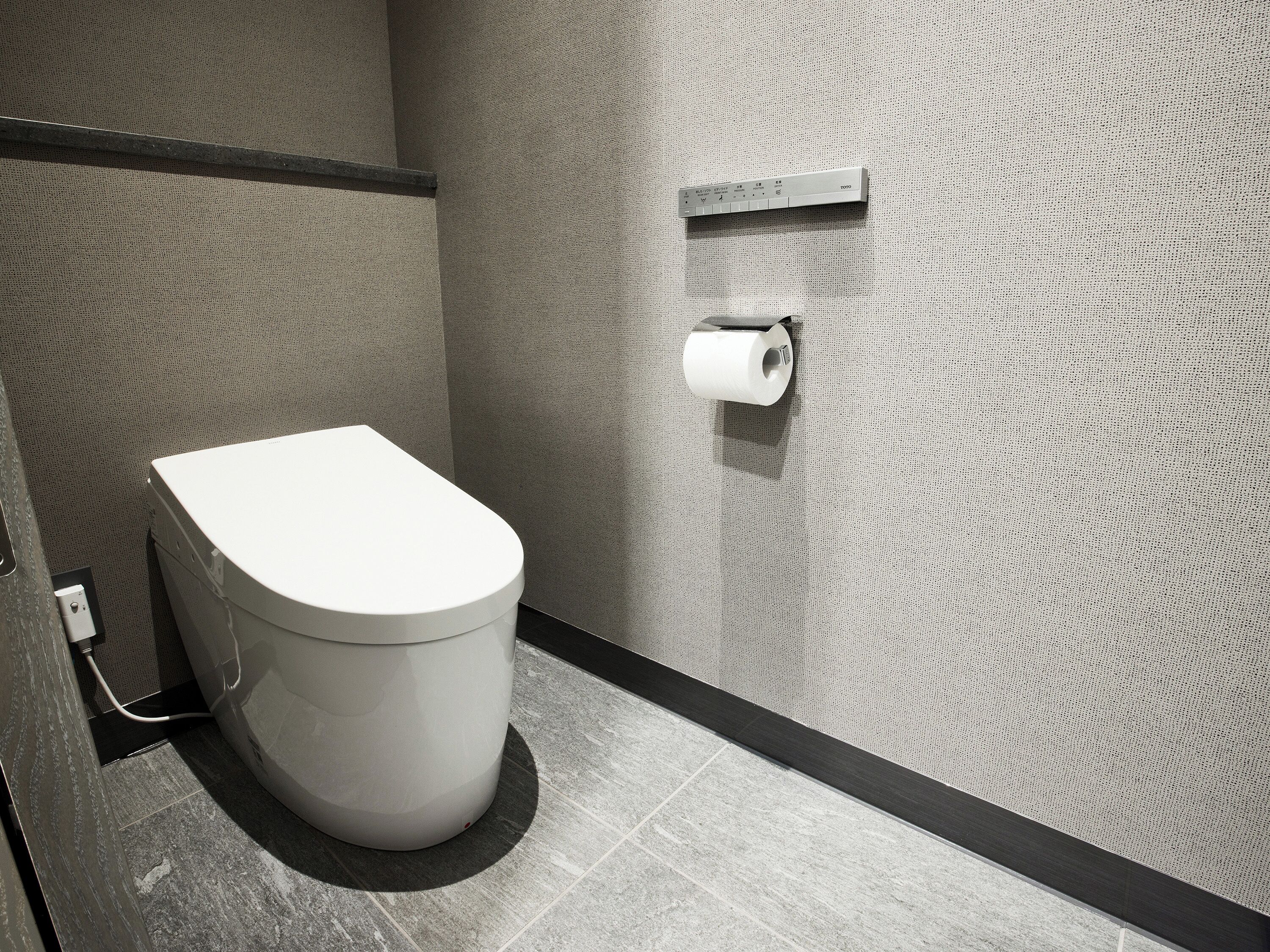 A modern bathroom with a toilet, a towel rack, and a toilet paper holder on the wall.
