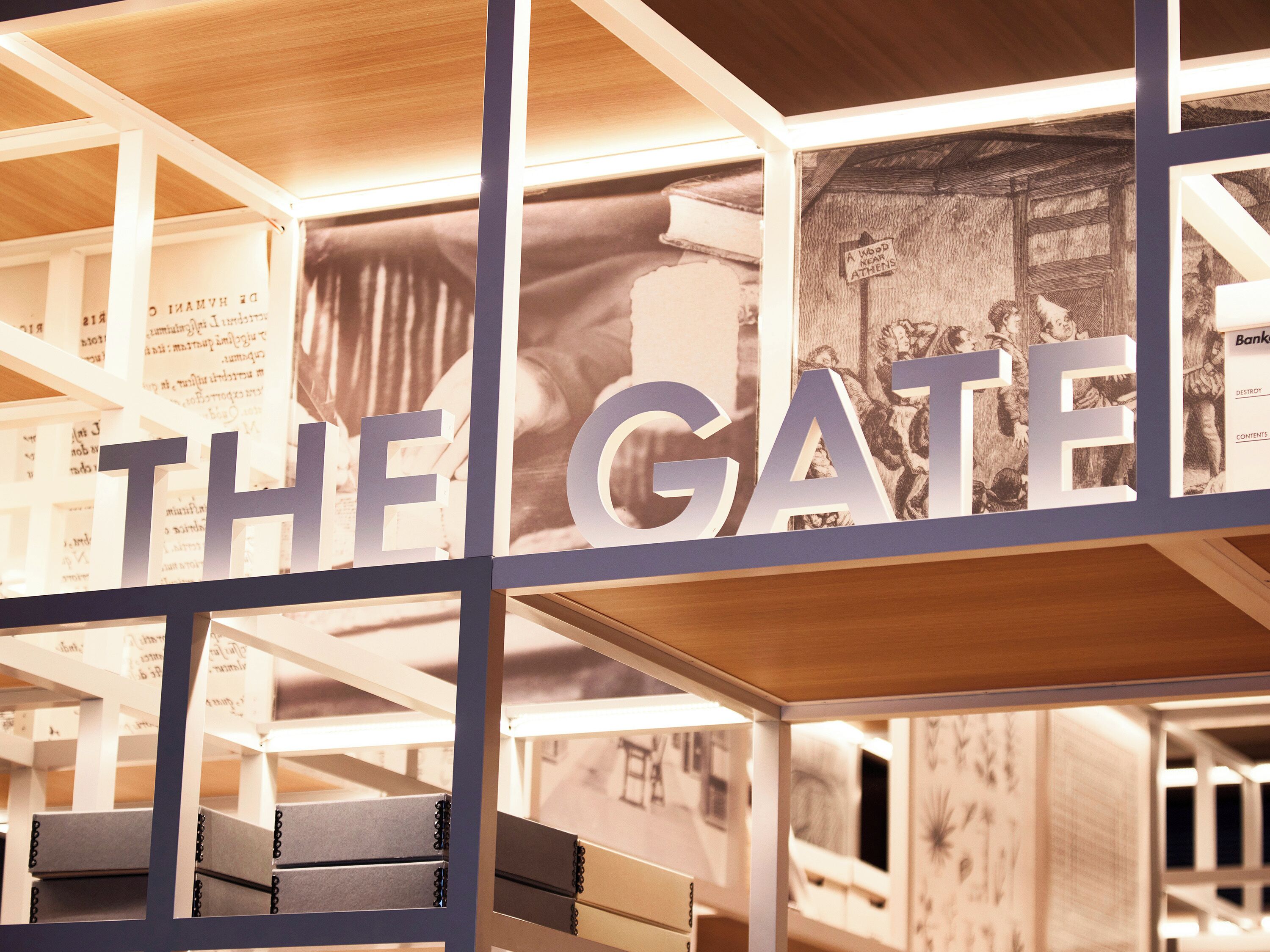 Um quarto com uma estante, uma cama e uma grande placa com a inscrição 'THE GATE'.