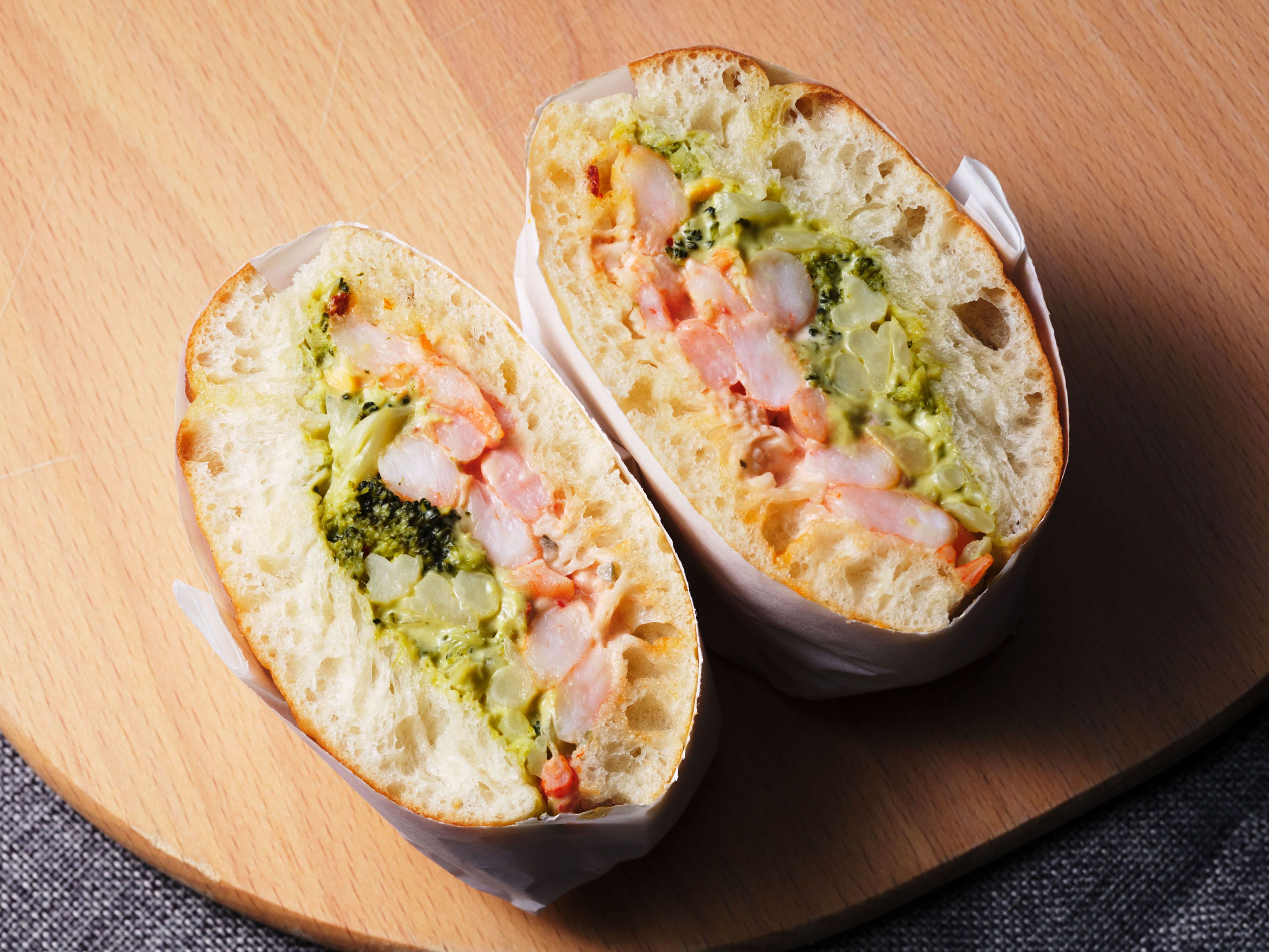 A sandwich cut in half on a wooden board.