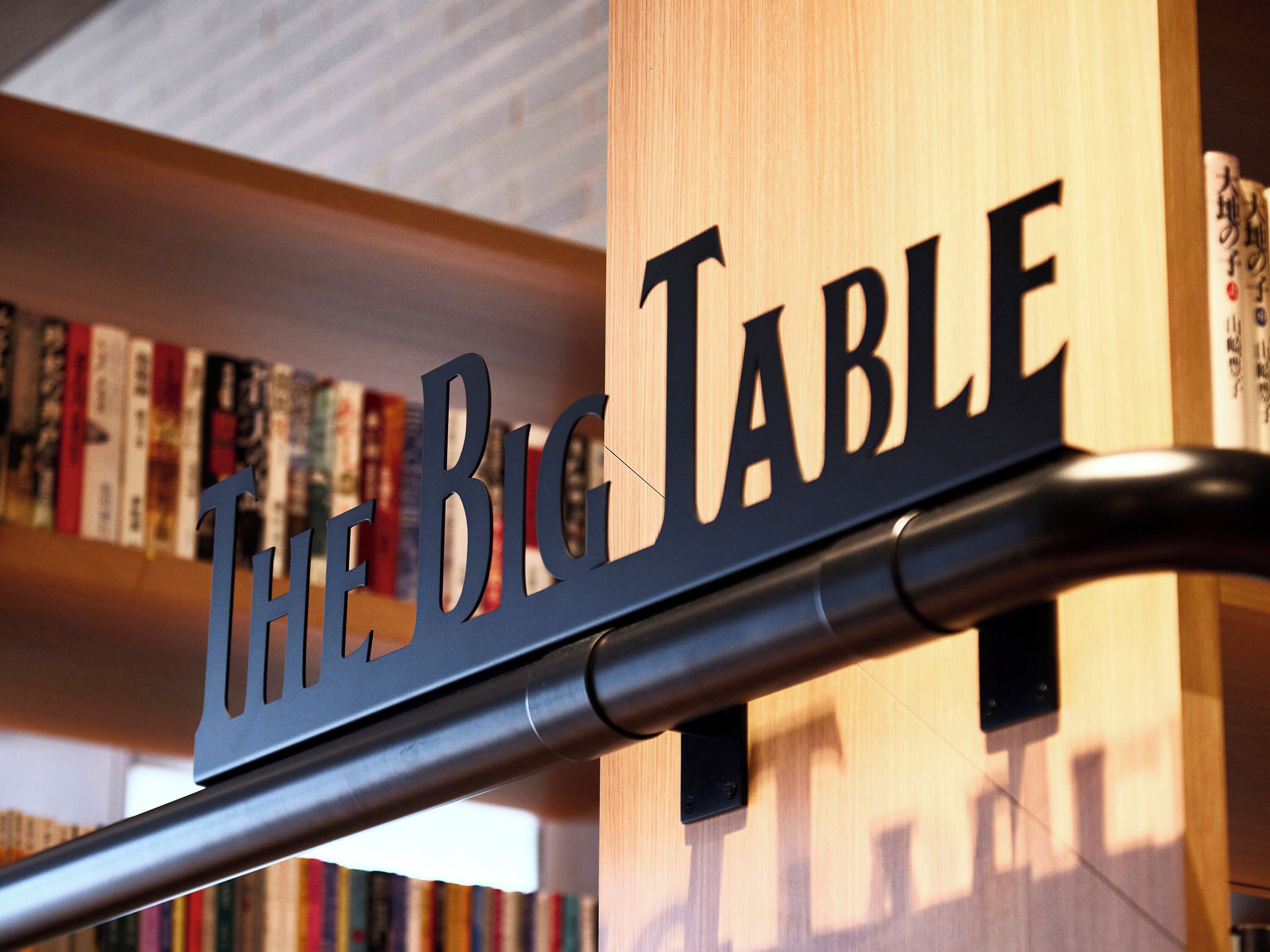 A bookshelf with books and a sign that reads "The Big Table".