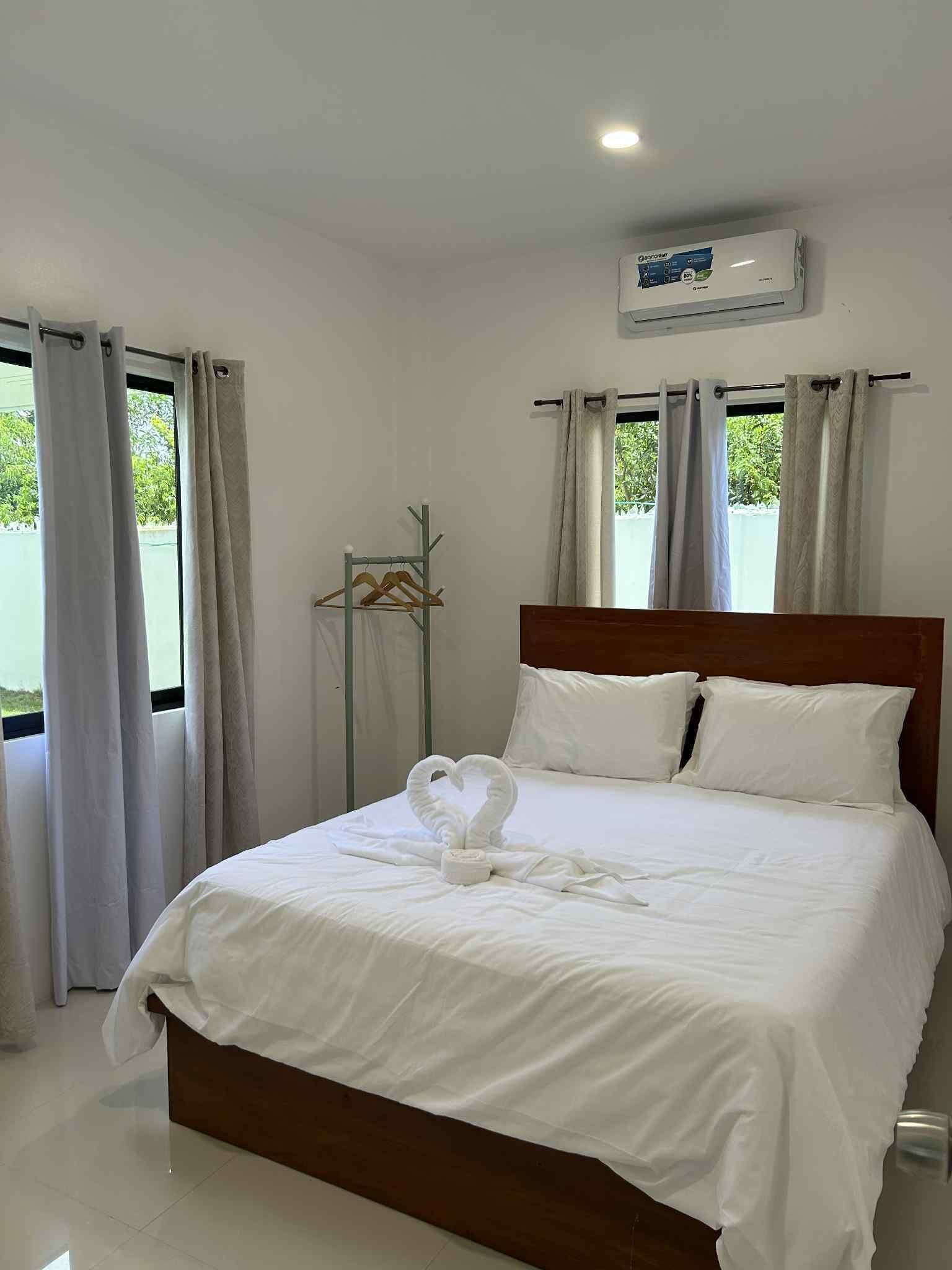Une chambre d’hôtel avec un lit bien fait, une tête de lit en bois et un climatiseur fixé au mur.