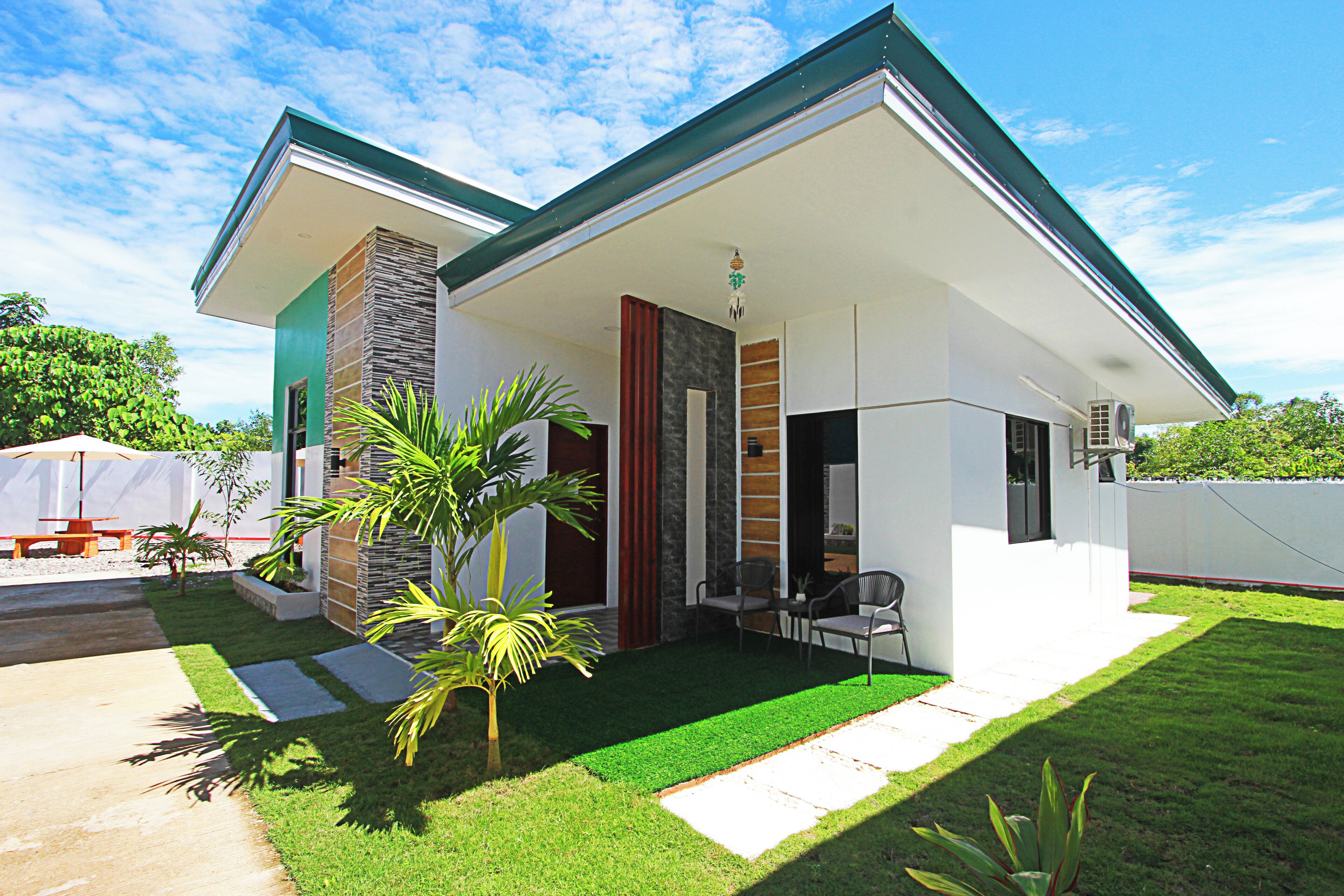 A modern house with a covered porch, a small garden, and a patio area.