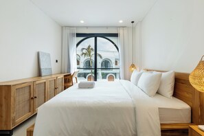 Een moderne hotelkamer met een groot bed, houten meubilair en uitzicht op een gebouw met bogen.