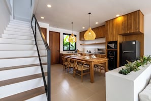 Een moderne keuken met houten kastjes, een centraal eiland en hanglampen.