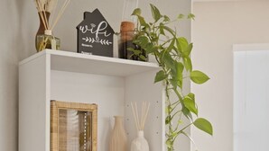 Et hvidt reolsystem med pynteting, en højttaler og en plante.