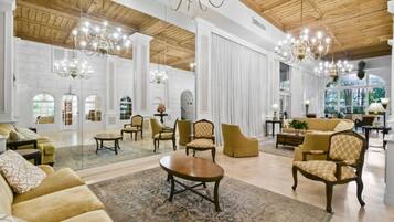 A spacious lobby with high ceilings, chandeliers, and a large seating area with sofas and armchairs.