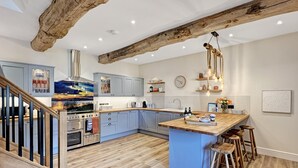 A modern kitchen with a central island, wooden beams, and a staircase. - Broomy Barn, Bromtpon Regis (Nr Dulverton)