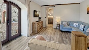 A spacious living area with a wooden ceiling, a blue sofa, and a wooden cabinet. - Broomy Barn, Bromtpon Regis (Nr Dulverton)