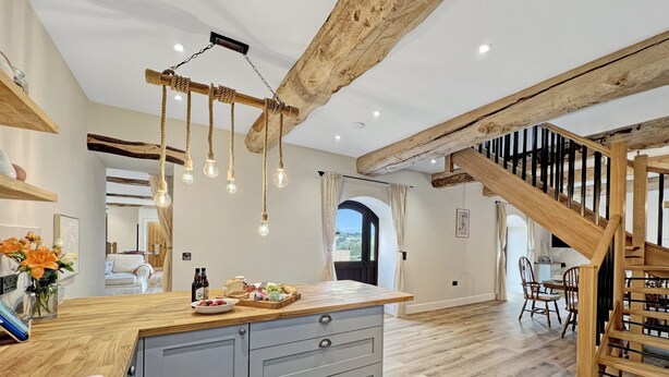 A spacious kitchen with a wooden island, grey cabinets, and a rustic ceiling. - Broomy Barn, Bromtpon Regis (Nr Dulverton)