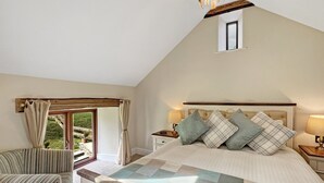 A bedroom with a large bed, a chair, a window, and a small skylight. - Broomy Barn, Bromtpon Regis (Nr Dulverton)