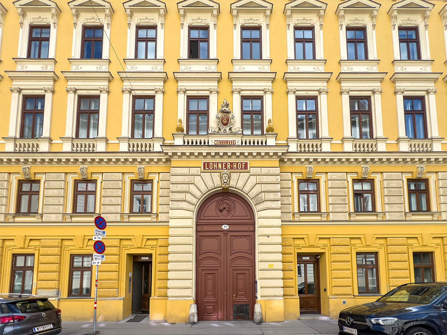 A yellow building with a large central door, multiple windows, and a sign reading "LOHNER-HOF".