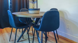 A dining area with a round table, four dark blue chairs, and a woven basket on the table.
