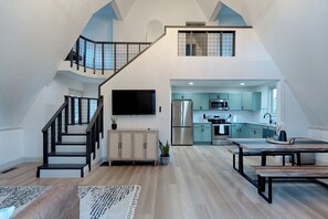 Un loft espacioso con cocina moderna, comedor y escalera que sube a un nivel superior.