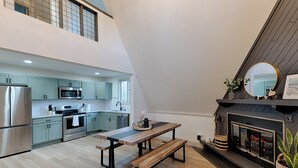 A modern kitchen with light green cabinets, stainless steel appliances, and a wooden dining table with benches.