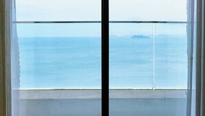 A window with a view of the sea and distant land. - TMS QUY NHON- RUBY LUXURY SEA APARTMENT (Quy Nhon)