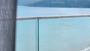 A coastal view with a mountain range in the background, a beach, and a railing. - TMS QUY NHON- RUBY LUXURY SEA APARTMENT (Quy Nhon)
