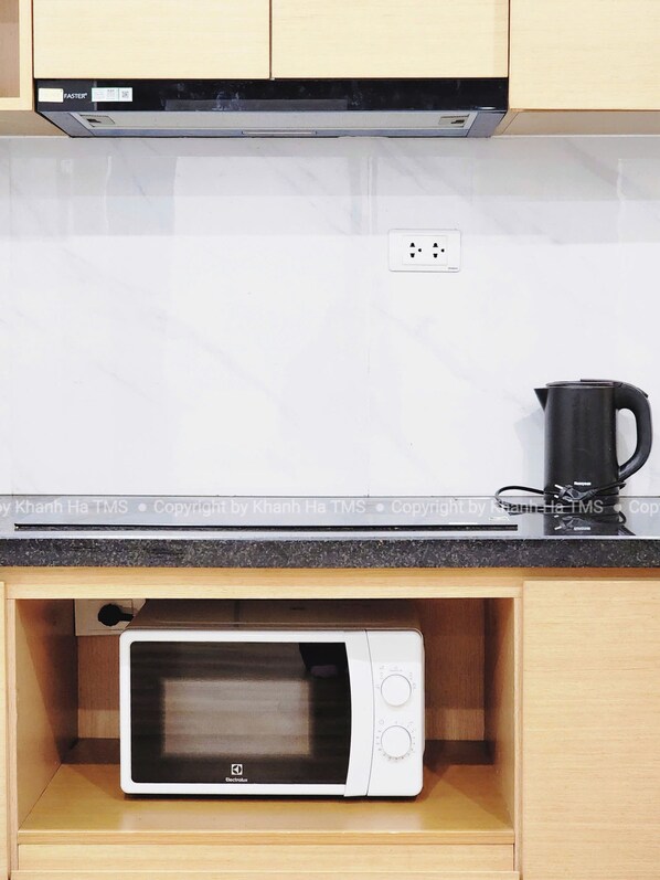A compact kitchen with a microwave, a coffee maker, and a power outlet on the countertop. - TMS QUY NHON- RUBY LUXURY SEA APARTMENT (Quy Nhon)