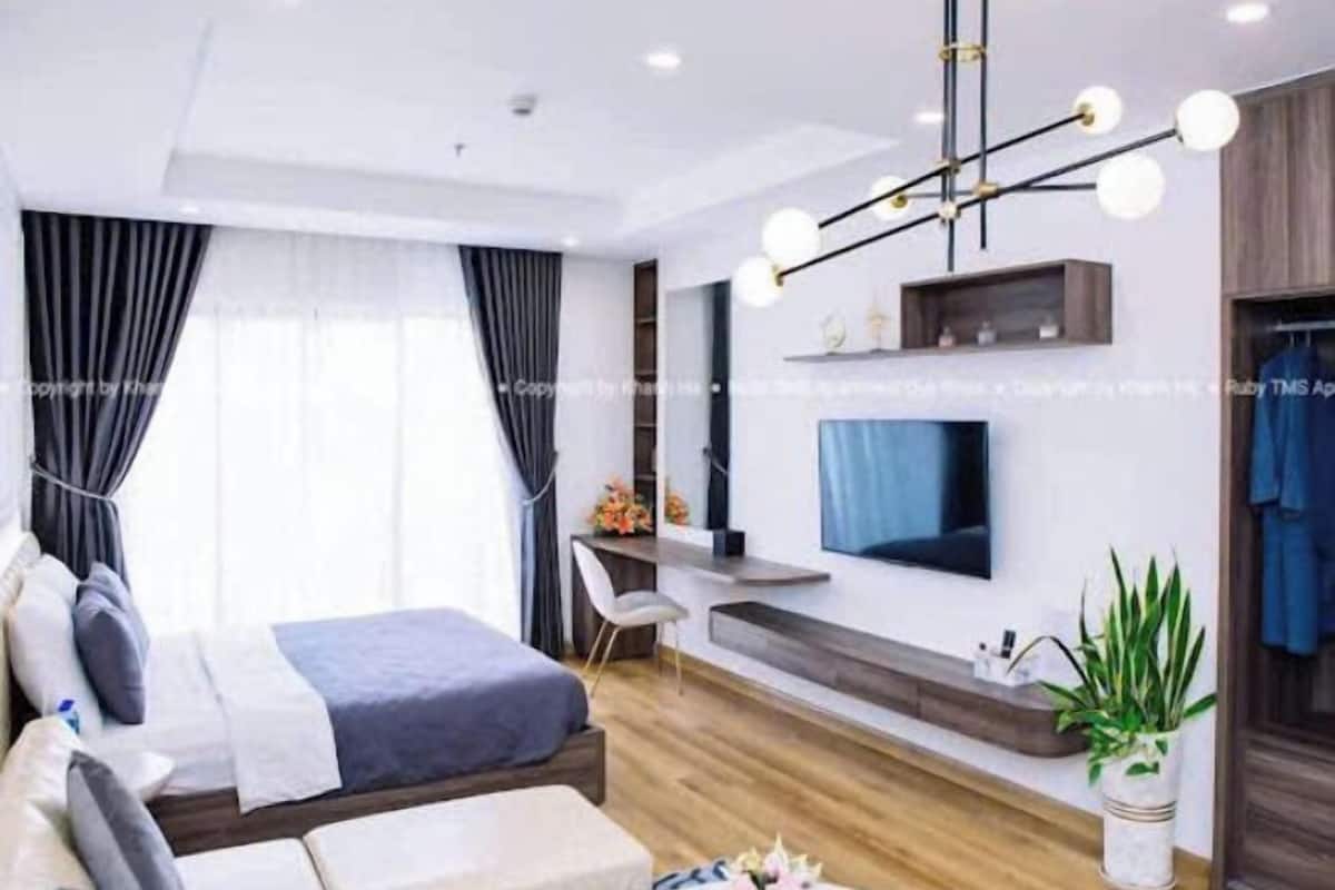 A modern bedroom with a bed, bedside table, and a desk area.