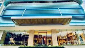 A tall, modern hotel with a prominent curved entrance and multiple floors. - TMS QUY NHON- RUBY LUXURY SEA APARTMENT (Quy Nhon)
