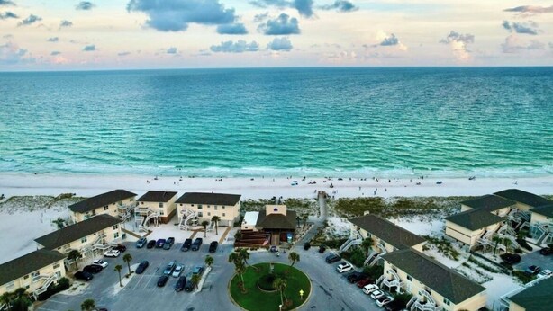 A beachfront hotel with multiple buildings, a parking area, and a view of the ocean. - NEWLY RENOVATED 2BR 2BA CONDO - FREE BEACH SERVICE (Destin)