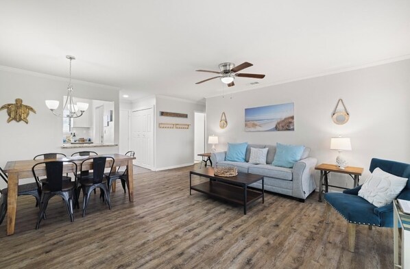 A spacious living area with a wooden dining table, a sofa set, and a coffee table. - NEWLY RENOVATED 2BR 2BA CONDO - FREE BEACH SERVICE (Destin)