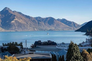 A coastal town with mountains in the background, a body of water, and buildings with flat roofs.
