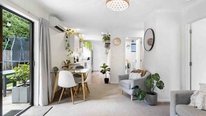 Una sala moderna con comedor, un sofá gris y un amplio ventanal con cortinas.