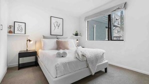 Un dormitorio minimalista con una cama grande, mesitas de noche y obras de arte en las paredes.