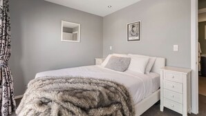 A bedroom with a bed, a nightstand, a mirror, and a picture on the wall. - Balla-Rama Stunning Views - Town Center - Parking (Queenstown)