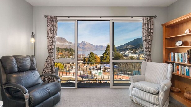 A living room with a large sliding glass door leading to a balcony with a mountain view. - Balla-Rama Stunning Views - Town Center - Parking (Queenstown)