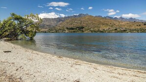 Um lago límpido com uma praia de areia e uma montanha ao fundo.
