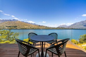 Eine Terrasse mit Tisch und Stühlen mit Blick auf einen See, im Hintergrund Berge.