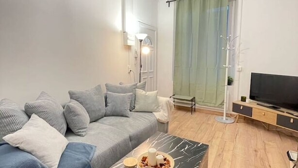 Ett modernt vardagsrum med en grå soffa, ett soffbord i marmor och en tv.