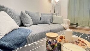 Ett vardagsrum med en grå soffa, ett soffbord med en skål med snacks och ett ljus.