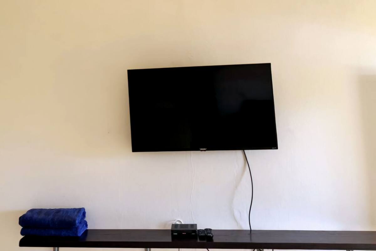 Un televisor de pantalla plana montado en la pared sobre una mesa de madera oscura.