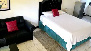A hotel room with a bed, a black sofa, a small table, and a framed picture on the wall. - SeaEsta Negril (Negril)