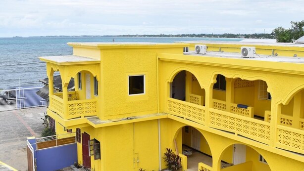 A yellow building with multiple balconies and a view of the sea. - SeaEsta Negril (Negril)