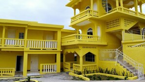 A multi-story yellow building with balconies, staircases, and a central courtyard. - SeaEsta Negril (Negril)