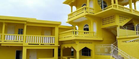 A multi-story yellow building with balconies, staircases, and a central courtyard.