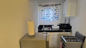A compact kitchen with a gas stove, a microwave, and a sink. - SeaEsta Negril (Negril)