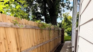 A wooden fence adjacent to a building with a concrete pathway. - Modern luxe townhome
-15 minutes away from downtown (Houston)