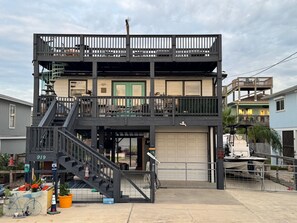A two-story building with a garage, a balcony, and a staircase leading to the upper floor.